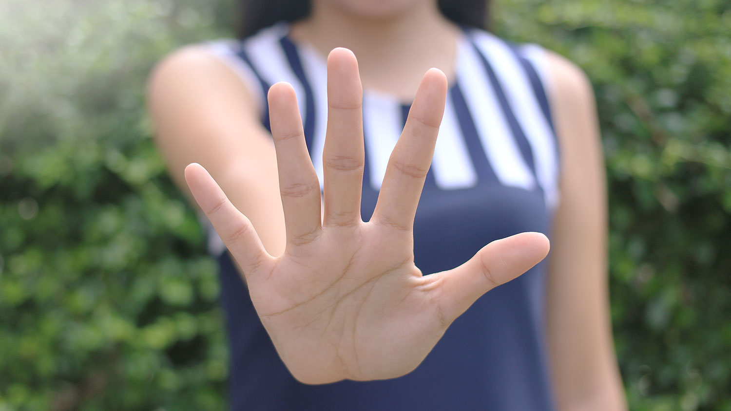 Hand with palm facing camera gesturing stop