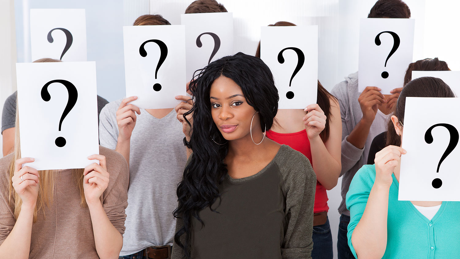 Young Black woman surrounded by White people with question mark signs over their faces