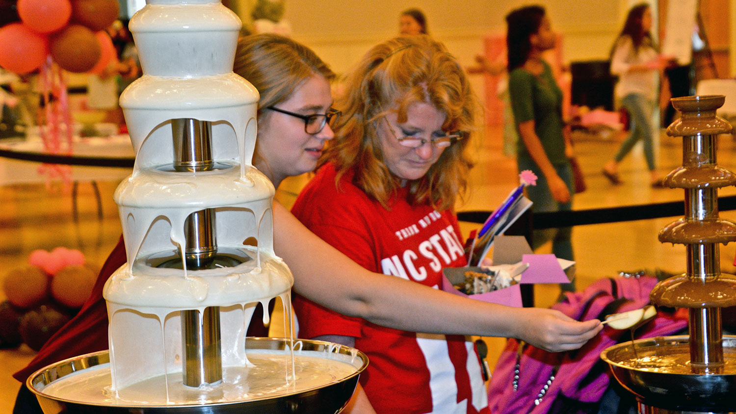 Woman dipping fruit into chocolate fountain at Chocolate Festival