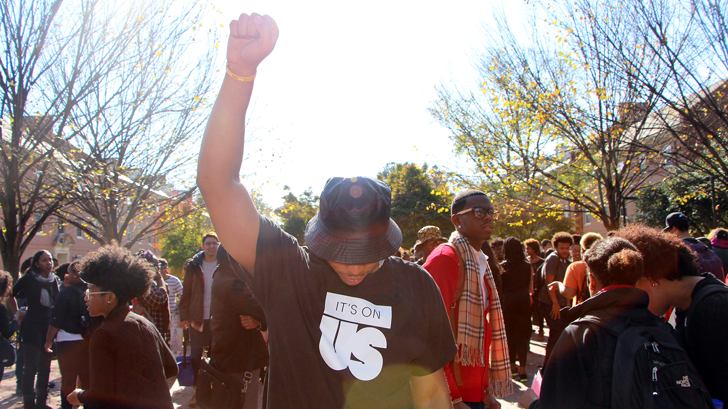 Student with fist raised and head down at rally