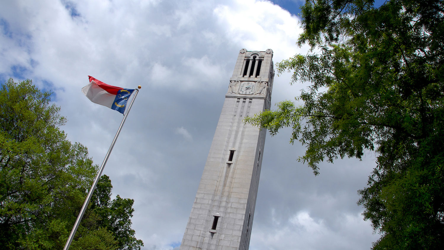 NC State Belltower on a cloudy day with state flag