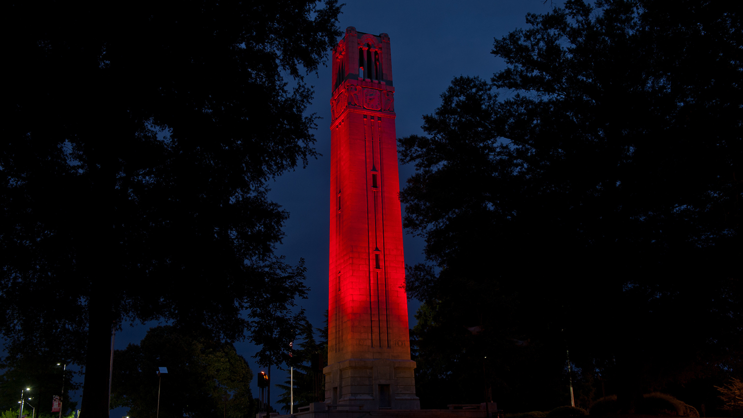 NC State Belltower lit up red at night