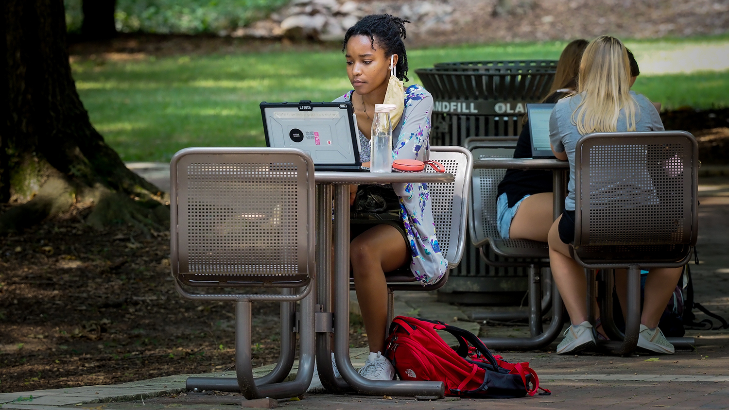 Young woman sitting outside at a table with laptop